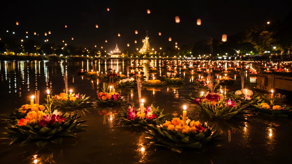 Loy Krathong: schwimmende Bananenblatt-Körbchen mit Kerzen auf dunklem Wasser