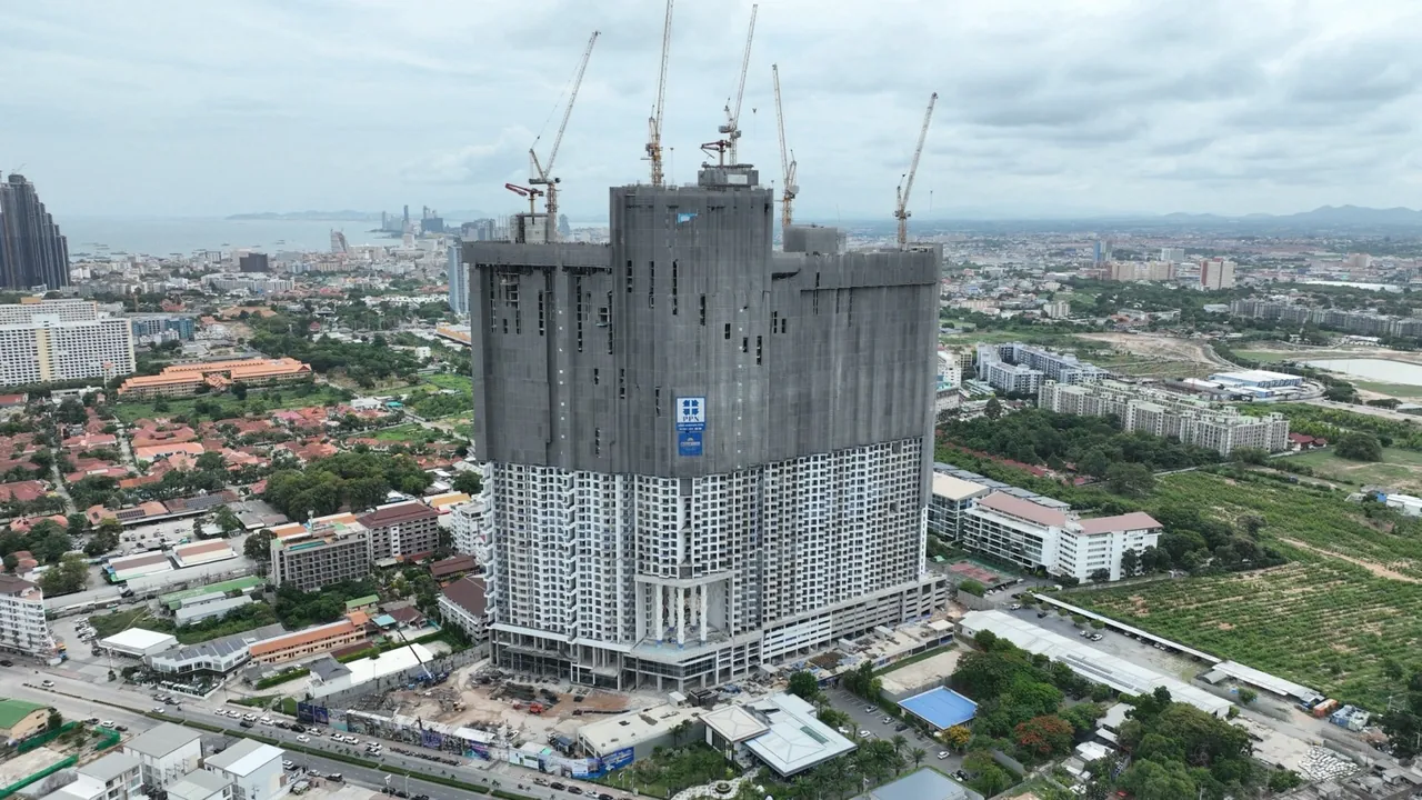 Copacabana Coral Reef Jomtien, construction progress August 2026, shell of the residential towers with cranes, city and sea in the background