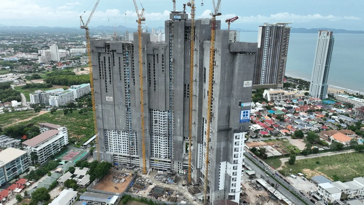 Copacabana Coral Reef Jomtien, construction progress August 2026, front view of the towers at full height, lower floors already clad in white facade